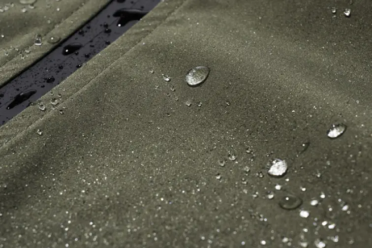 Gros plan d'un tissu vert imperméable avec des gouttes d'eau à sa surface.